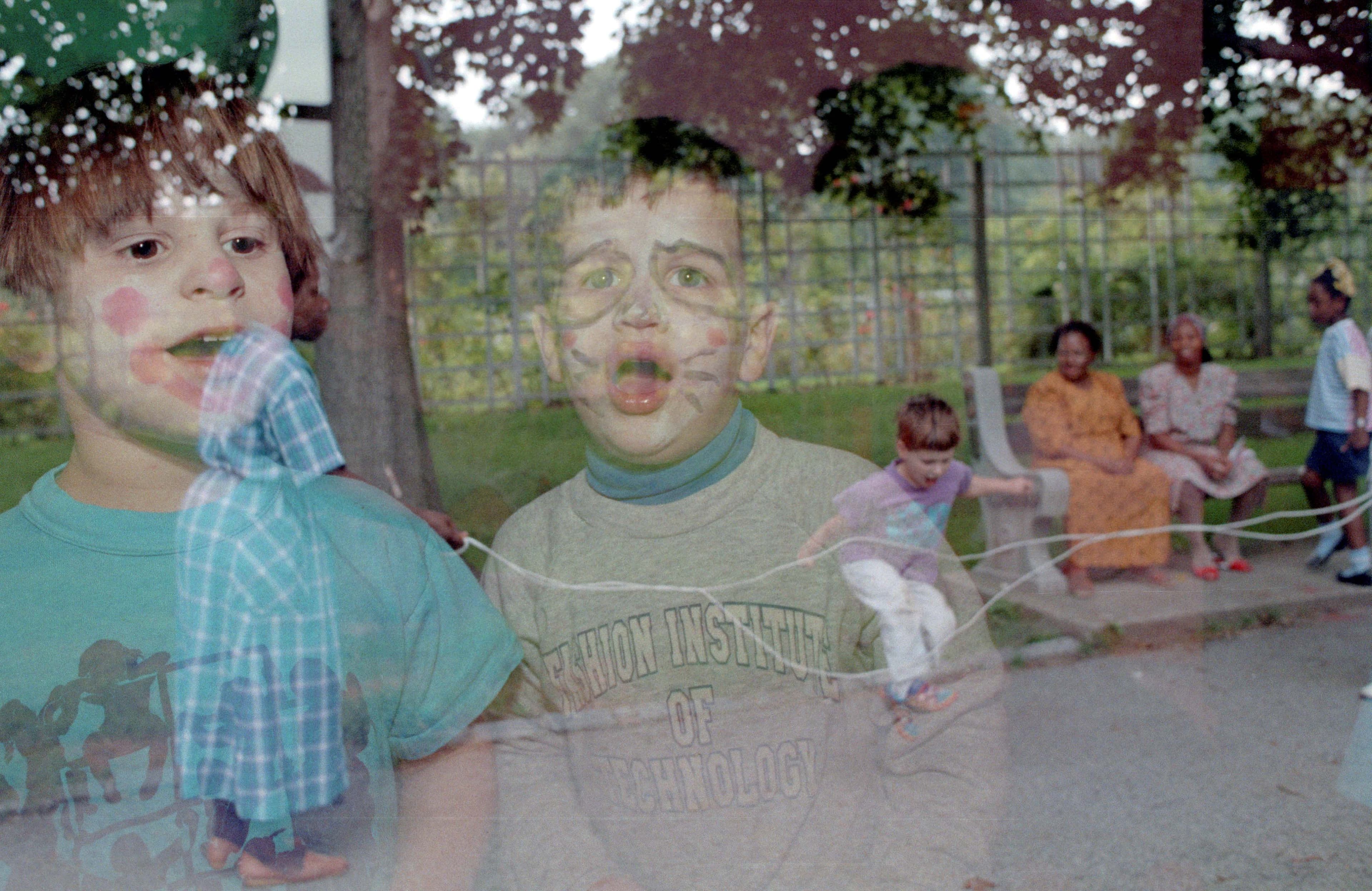 A layered double exposure of children and adults outdoors