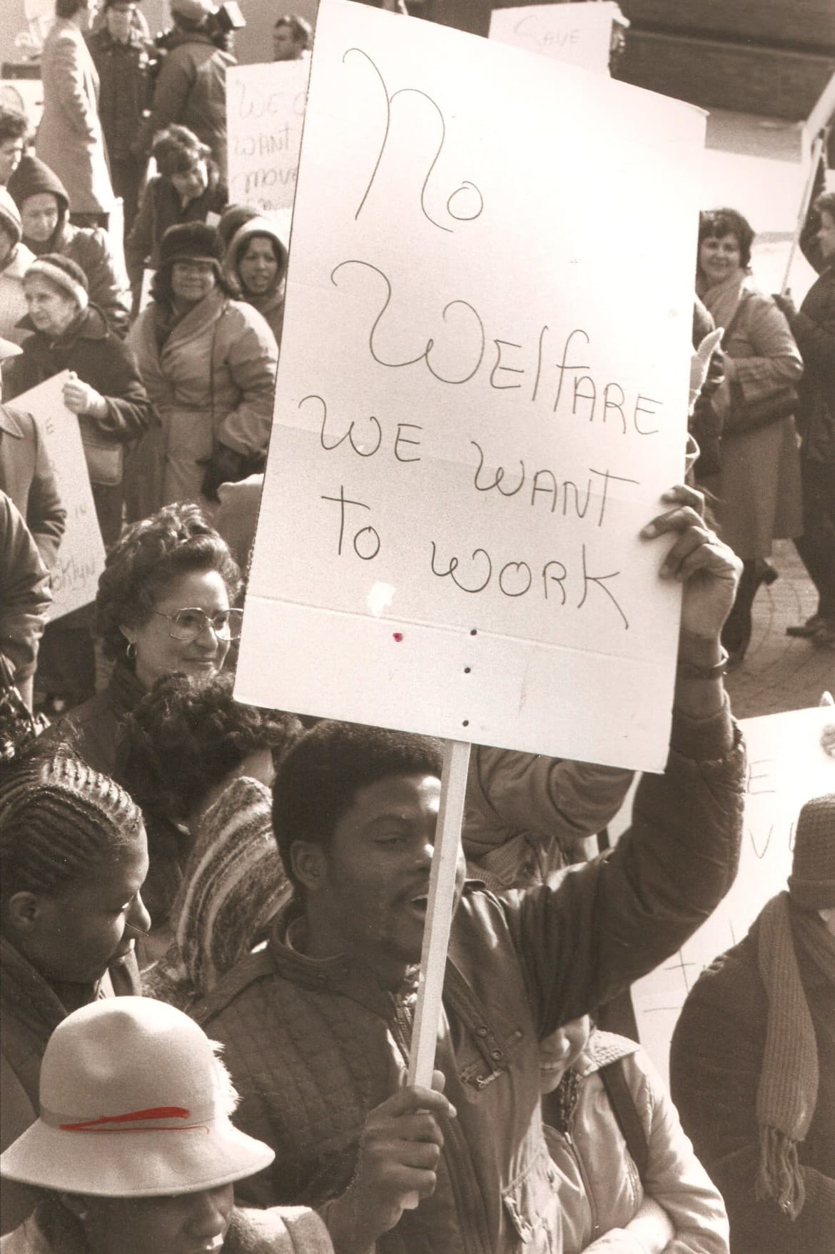 A protester holds a No Welfare, We Want to Work sign in a crowded demonstration